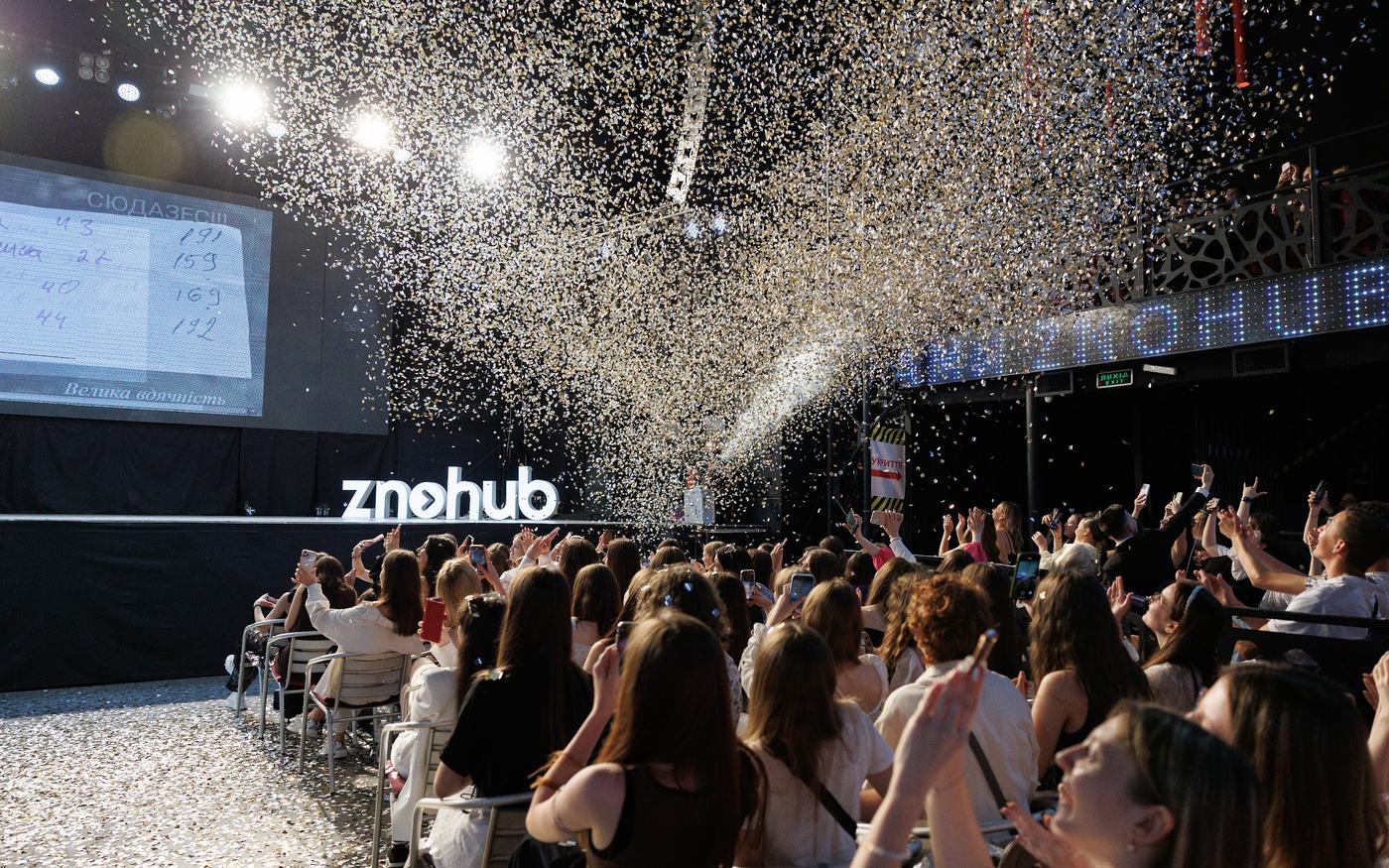 Учні на офлайн-зустрічі ZNOHUB: повна зала, конфеті та сцена з логотипом znohub